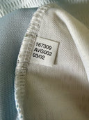 Soccer jersey collar label close-up, light blue fabric with size/ID tag