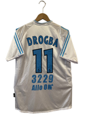 White back soccer shirt with “DROGBA” and number 11, plus “3229 AIIO 0M” text.
