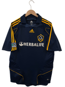 LA Galaxy away soccer jersey on hanger with LA crest and Herbalife sponsor front.