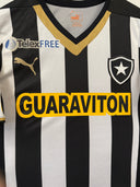 Black-and-white striped football shirt with yellow trim, sponsor text and crest