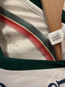 White soccer away shirt with green collar and red/green/black trim stripes