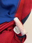 Home football shirt cuff label on red and navy striped fabric
