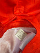 Red football shirt fabric detail with white adidas size and care label