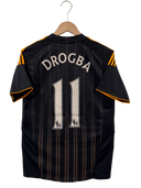 Black football away jersey with orange trim, "DROGBA" and number 11 on back